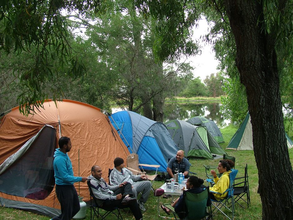 A group of friends enjoy camping on the large green grassy sites at Grampians Paradise Camping and Carvan Parkland